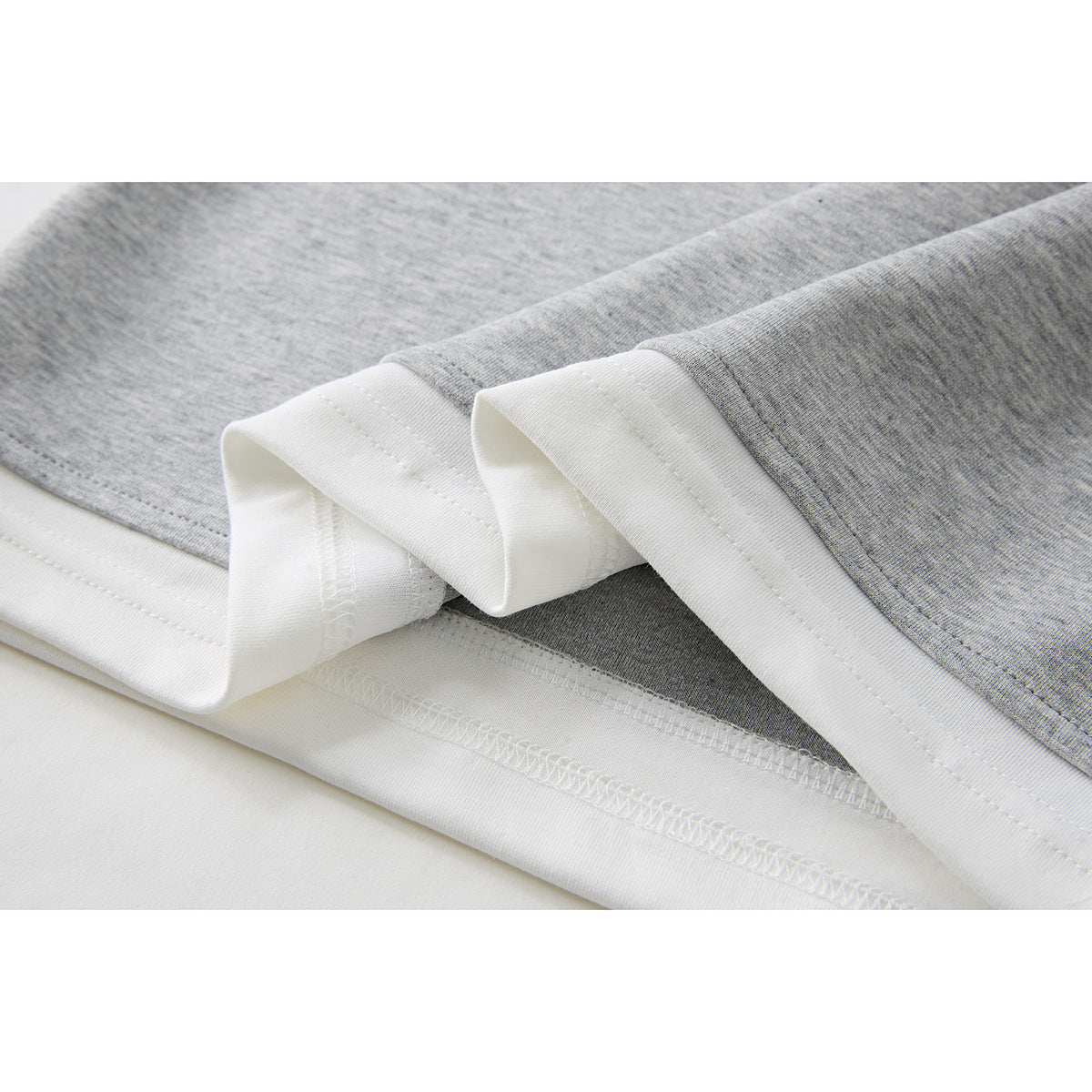 Close-up of the gray shirt fabric and white inner hem binding with visible stitching.