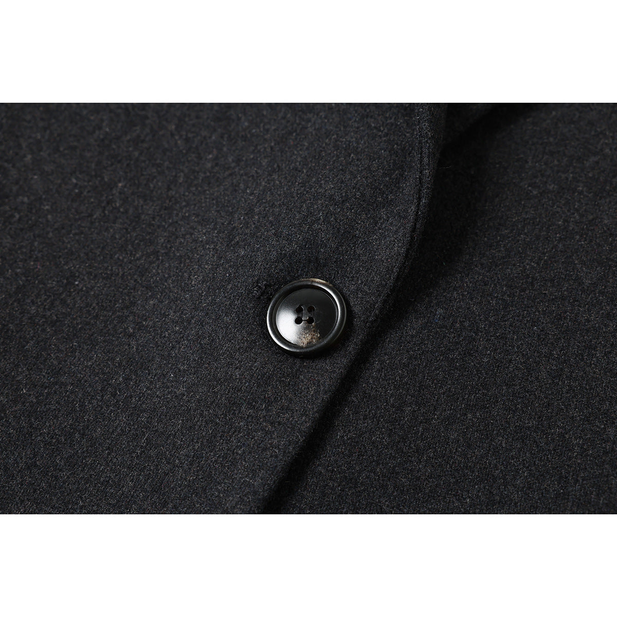 Close-up of a glossy black four-hole button on charcoal gray coat fabric.