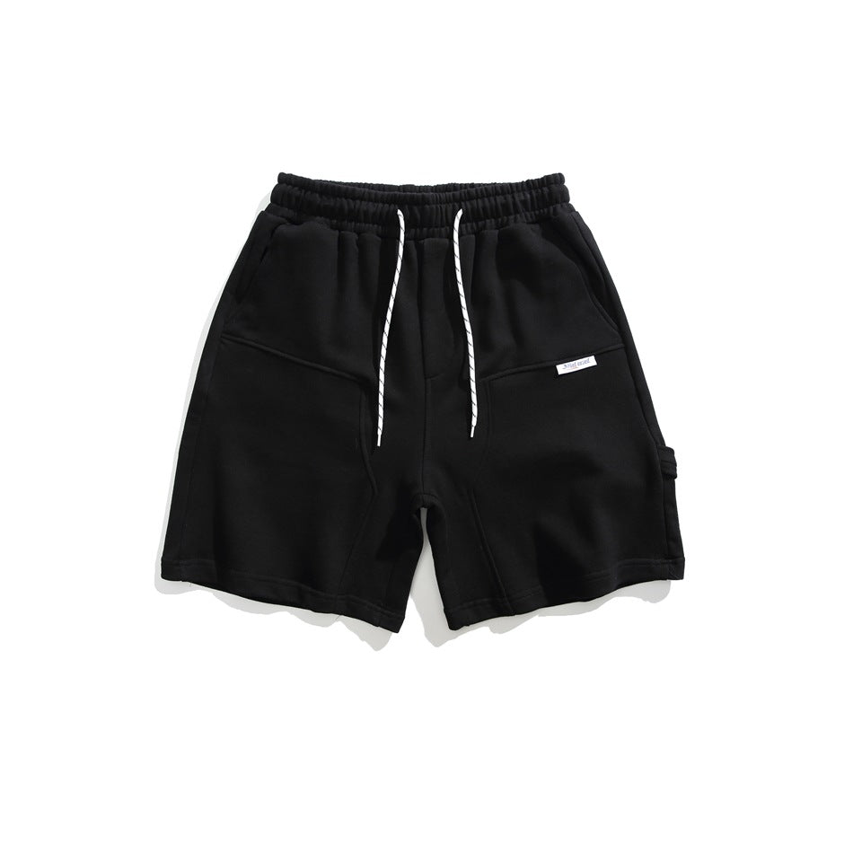 Black drawstring shorts with elastic waist, curved front seams and a small white label, flat lay front view