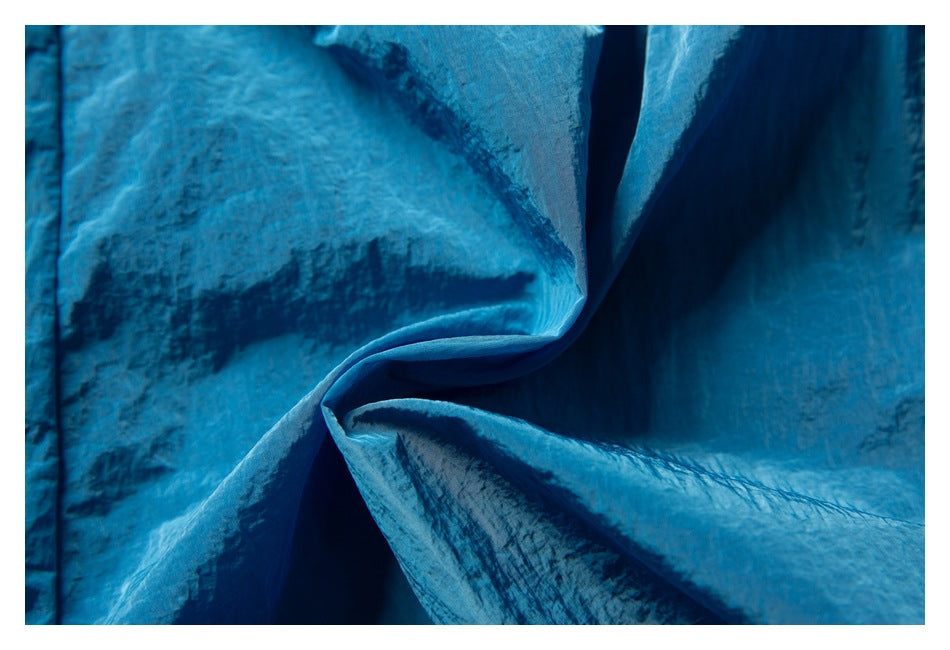 Close-up of textured blue fabric folded and gathered, showing its surface and seams.
