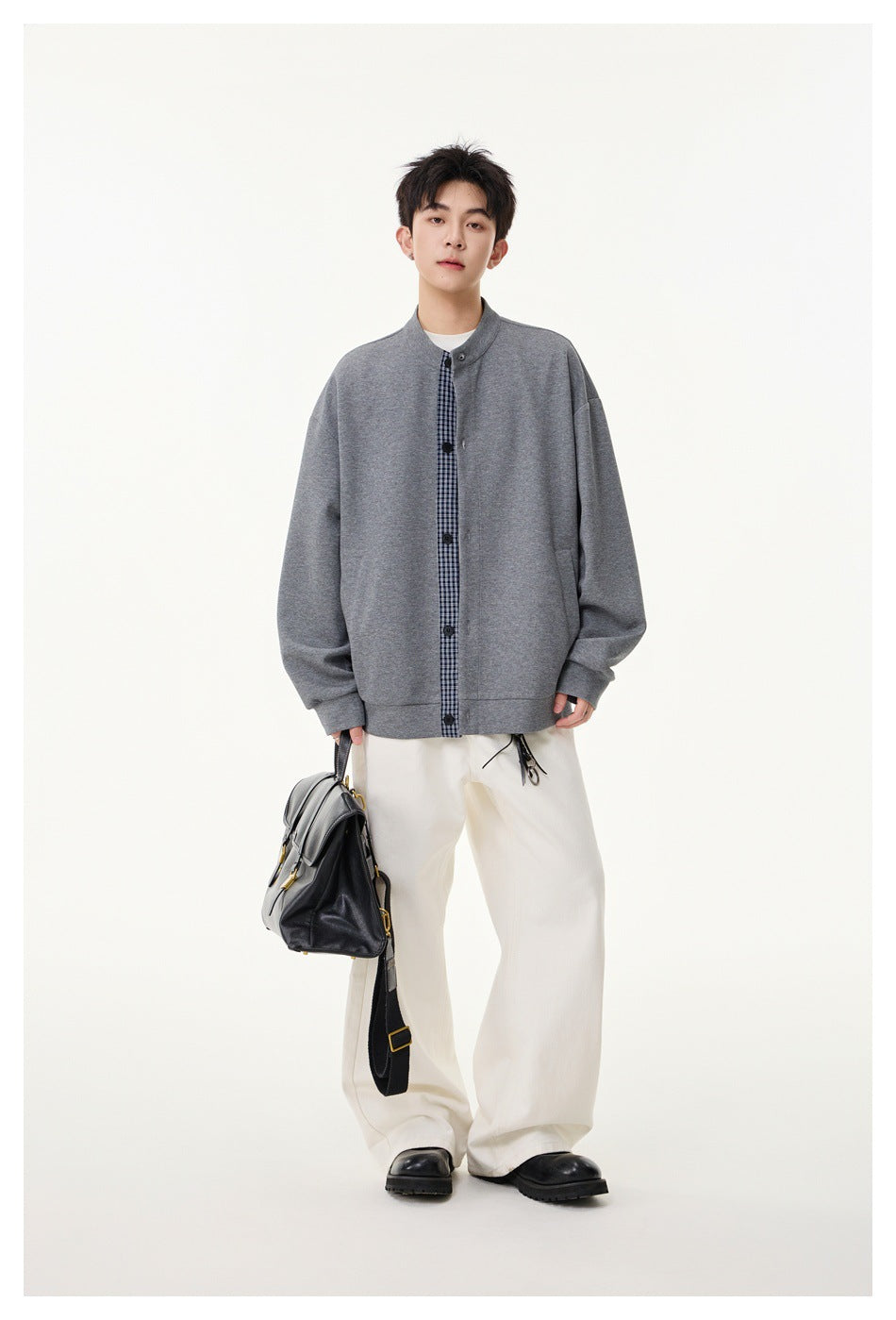 Model standing in a gray stand-collar button jacket with navy gingham placket, cream wide pants and black boots