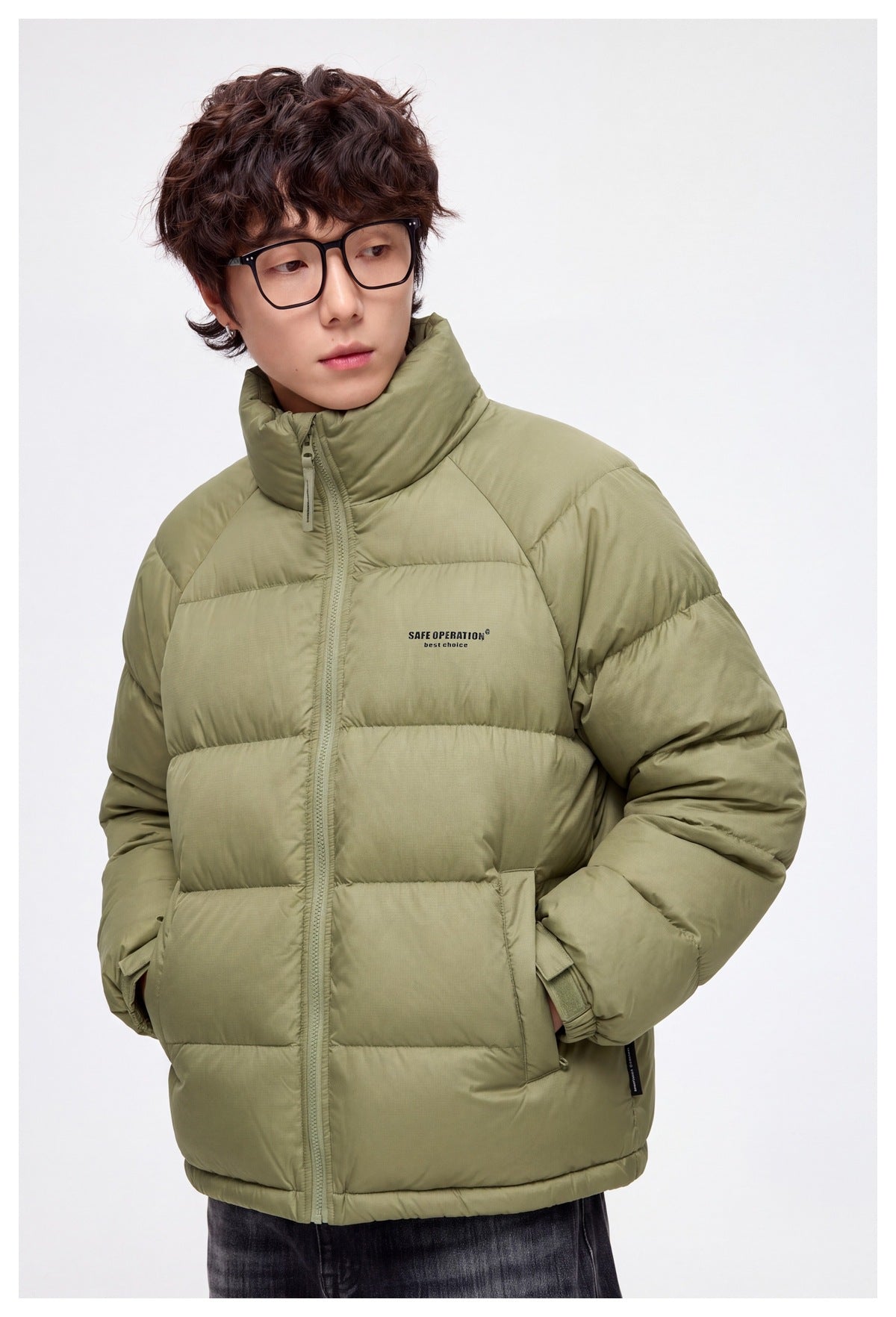 Close view of a model wearing a light olive quilted puffer jacket with a high collar, zip front and flap pockets.