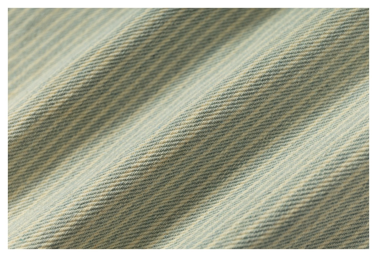 Macro view of the diagonal weave and faded pale blue and tan stripes in denim fabric.