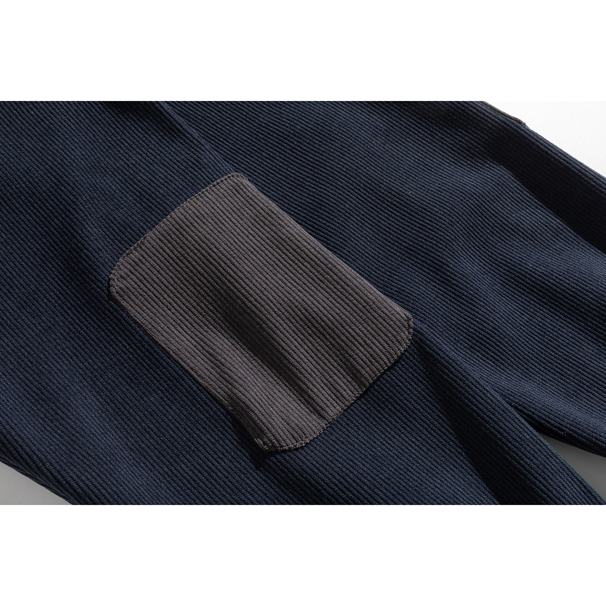 Close-up of a gray rectangular patch on the navy pullover’s ribbed fabric.