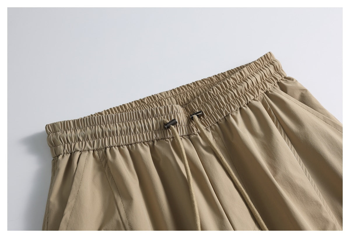 Close-up of tan pants with a gathered elastic waistband and adjustable drawstrings.