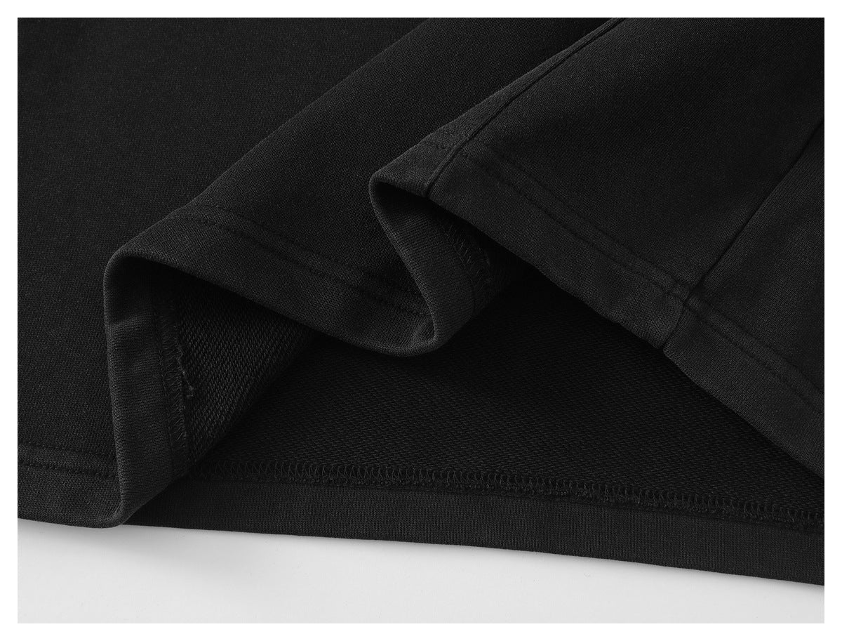 Close-up of a black garment hem folded back to show the stitching and inner fabric.
