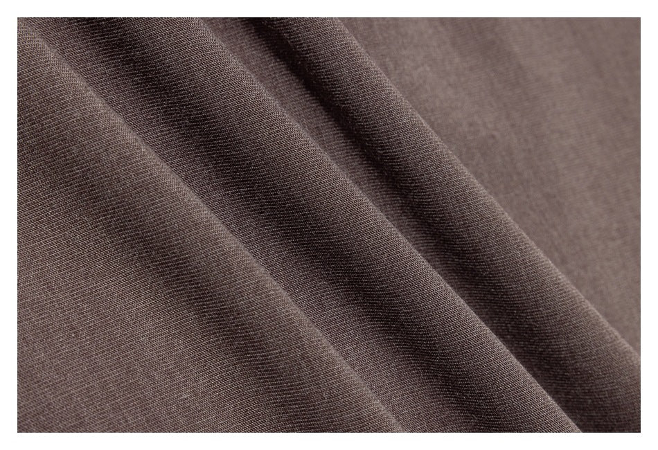 Close-up of taupe-brown garment fabric draped in soft folds, showing its surface texture.