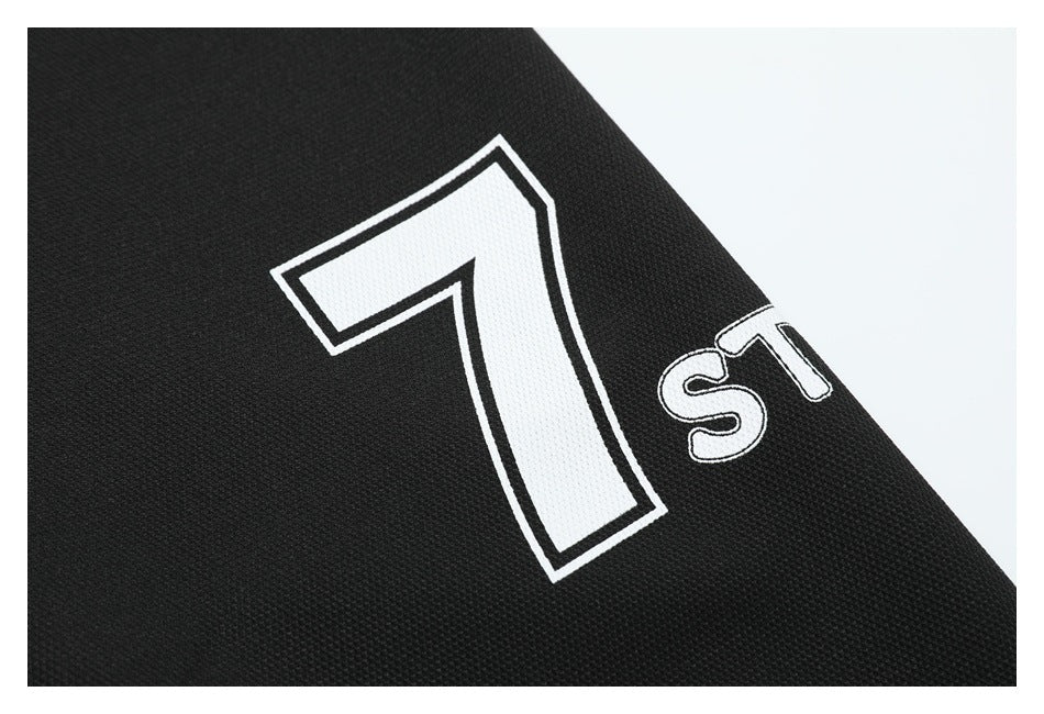 Close-up of black fabric with a large white outlined number 7 and partial lettering.