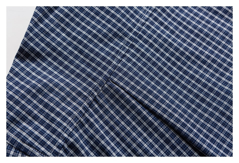 Close-up of navy fabric with a fine white and gray plaid pattern and a stitched seam.