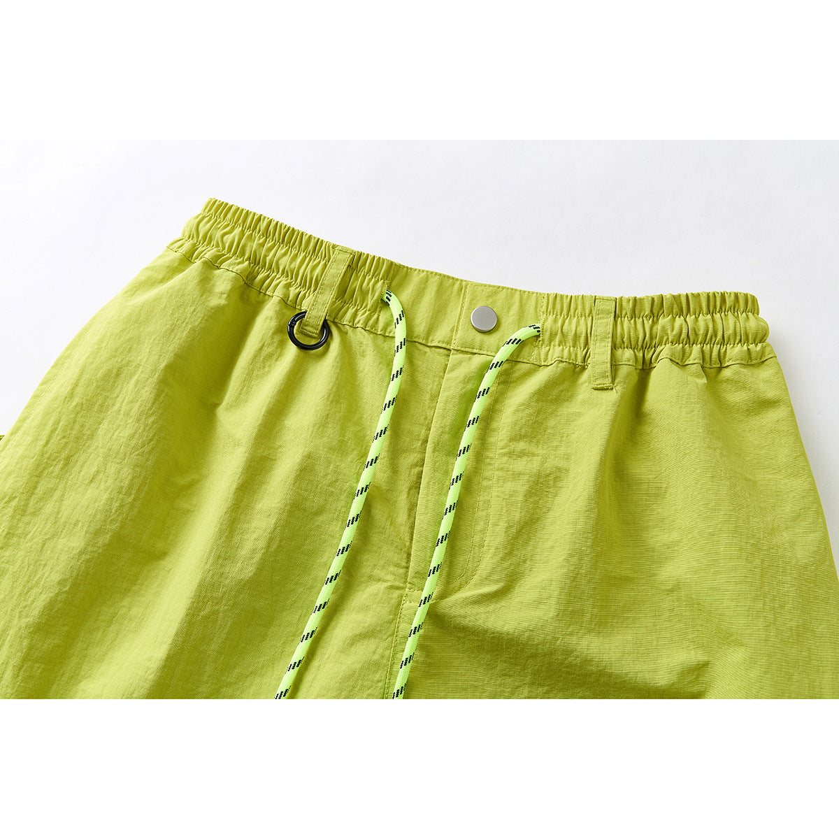 Close-up of lime green trousers showing an elastic waistband, button, belt loops, black ring, and striped drawcord.