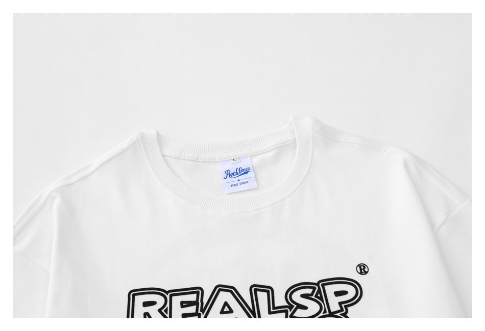 Close-up of the white T-shirt's ribbed crew neckline, neck label, and partial black outlined chest lettering.