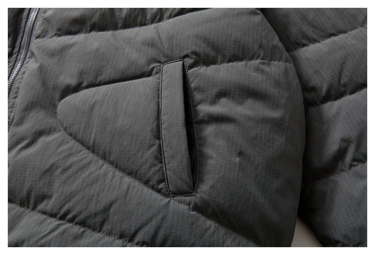 Close-up of a charcoal gray quilted jacket pocket with a vertical fabric tab.