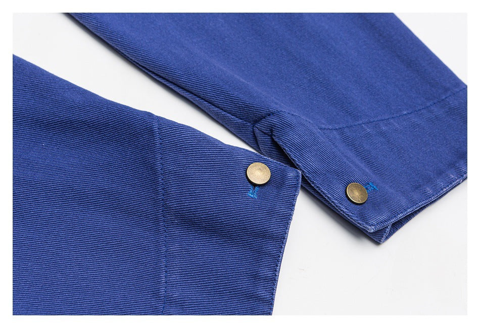 Close-up of two blue garment edges with brass-colored snap fasteners.