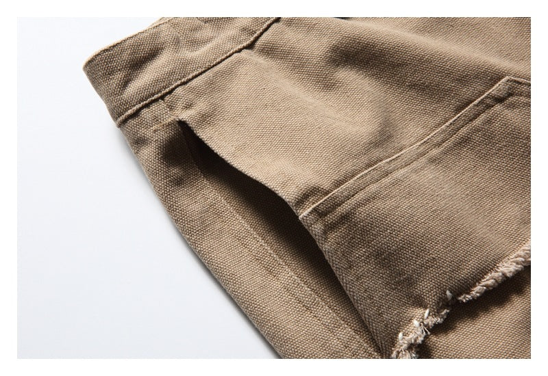 Close-up of tan trousers showing a seam, pocket edge, and frayed stitching.