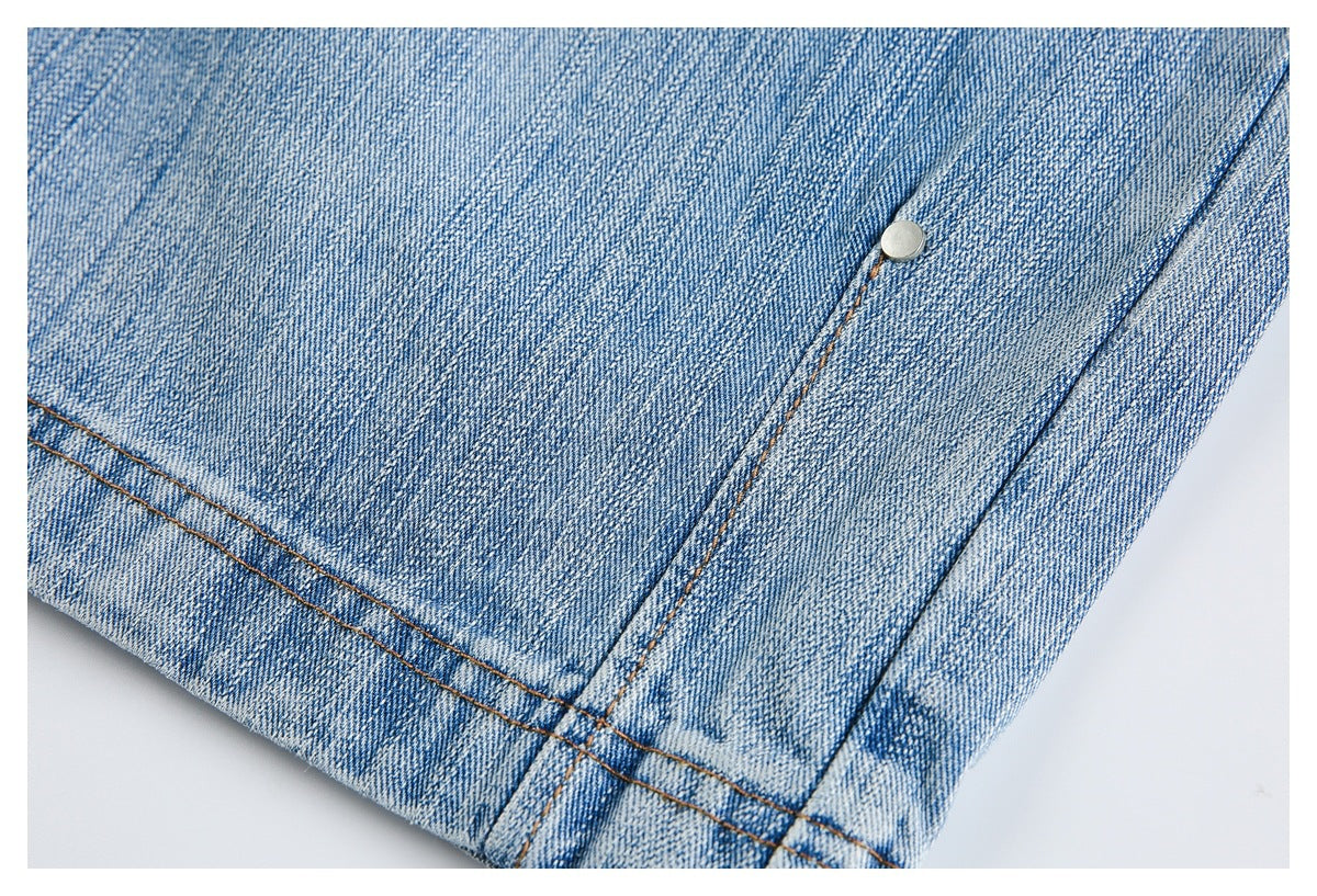 Close-up of a faded blue jeans leg hem with double stitching and a metal rivet.