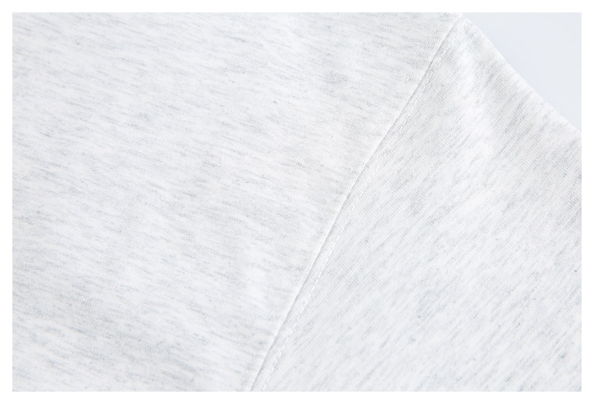 Close-up of the shoulder and sleeve seam on a white heathered knit top.