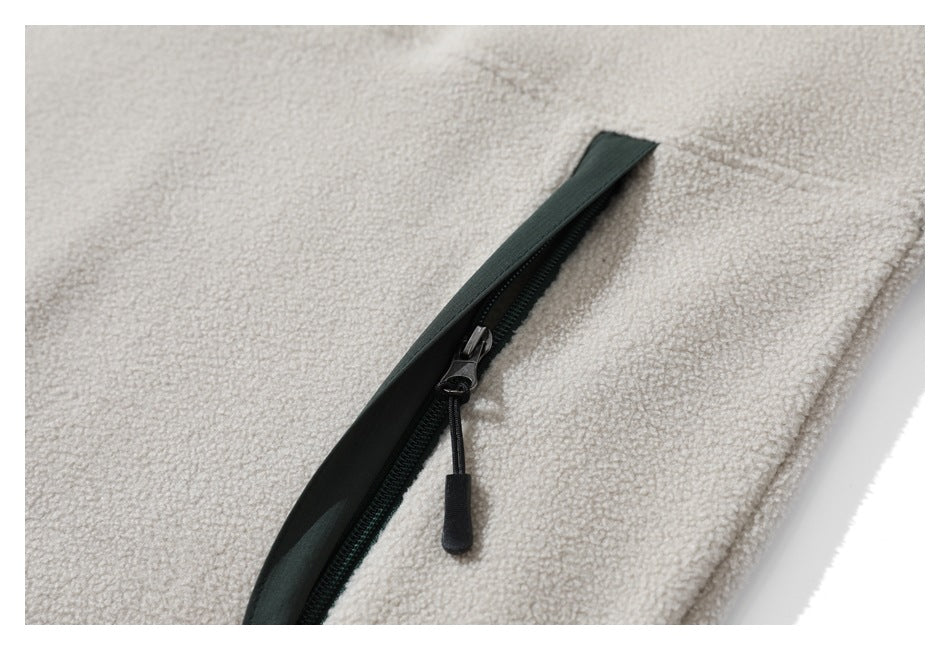 Close-up of a dark green-trimmed zipper on the cream sherpa jacket.