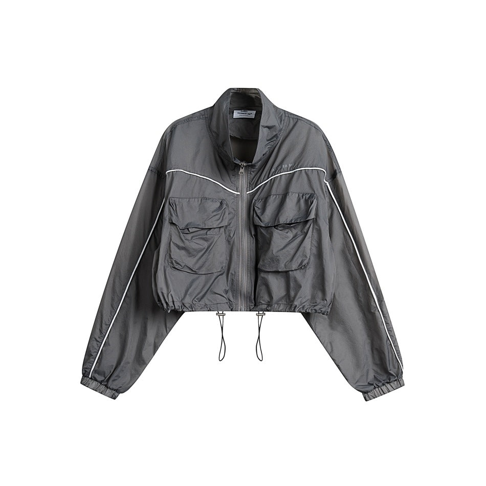 Light gray cropped zip jacket with stand collar, white piping, two flap chest pockets and drawstring hem on white background