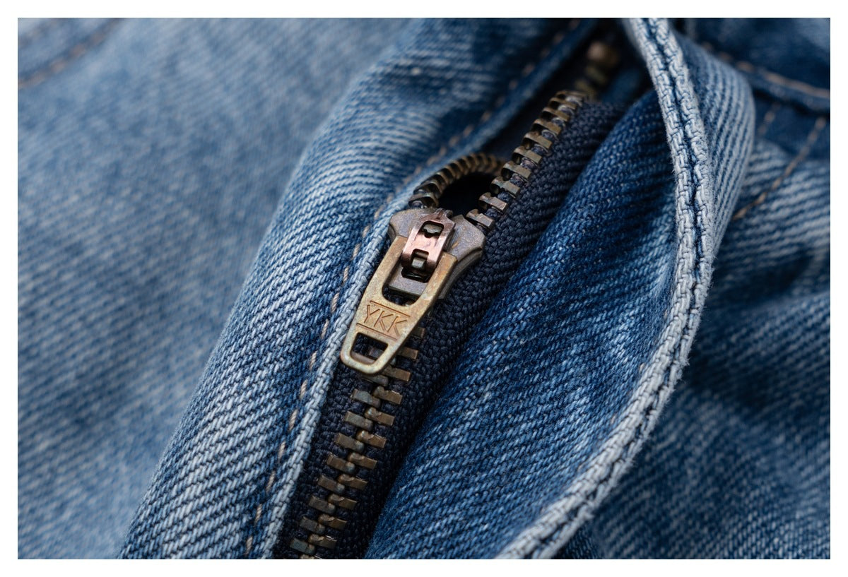 Close-up of the jeans fly showing a bronze-colored zipper on dark blue denim.