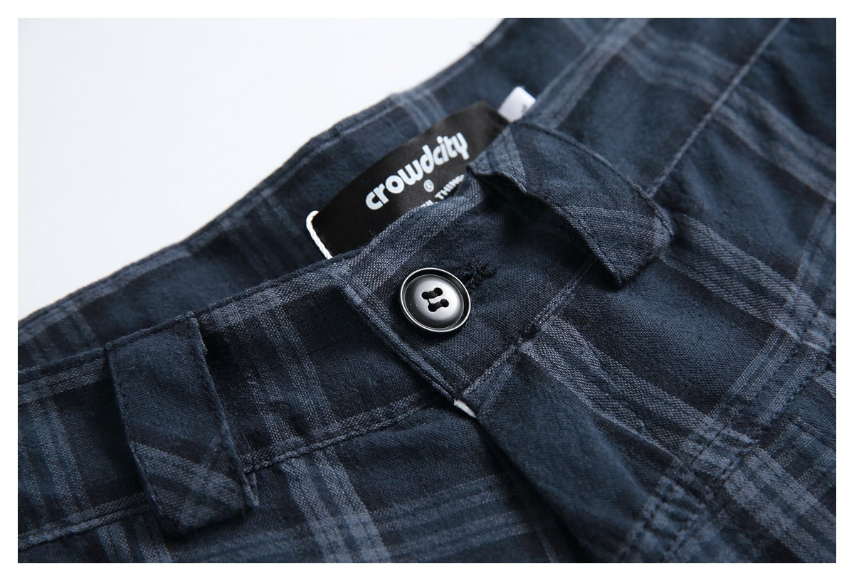 Close-up of dark navy plaid trousers showing the waistband, belt loops, button, and sewn-in label.