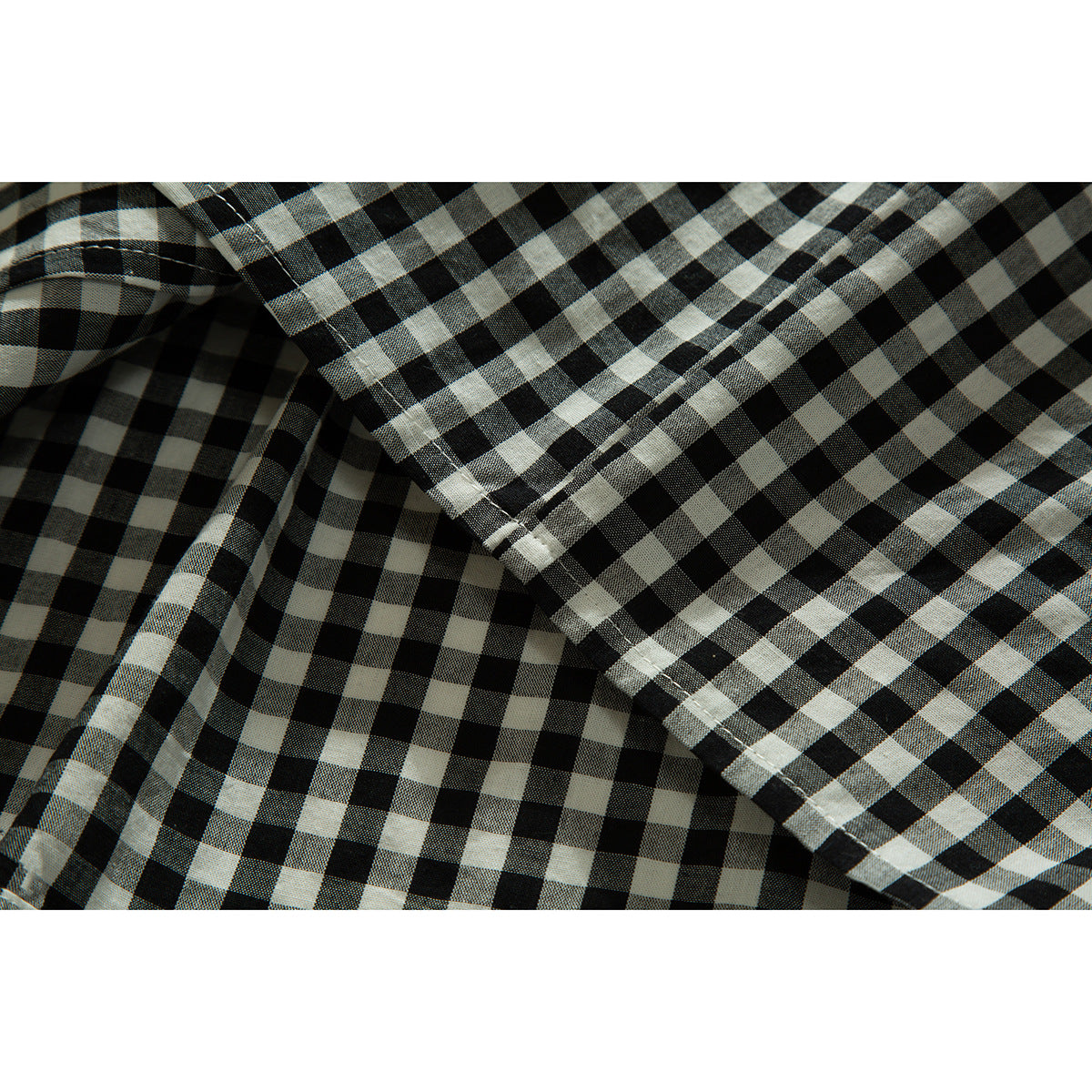 Close-up of black-and-cream checked shirt fabric showing seams and stitching.