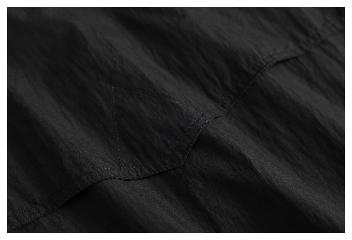Close-up of black fabric with a curved stitched seam and subtle surface texture.