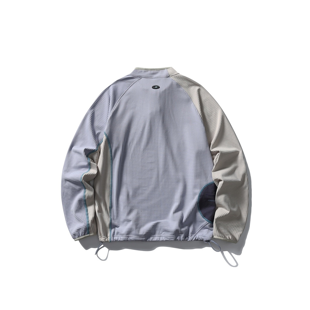 Back view of a pale gray jacket with cream sleeves, dark pocket accents, teal piping and adjustable drawcord hem.