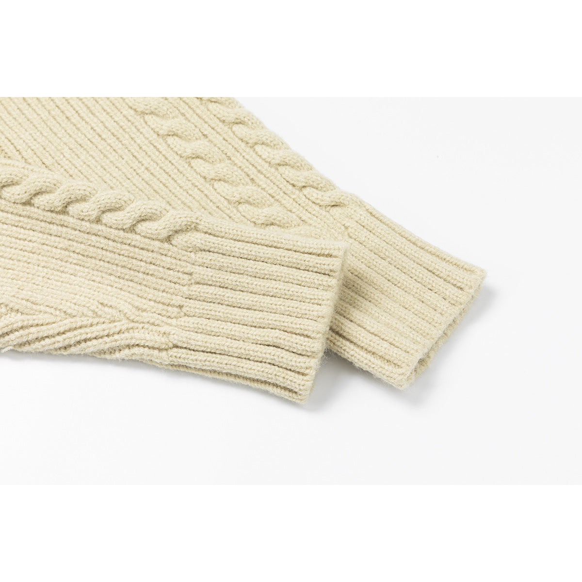 Close-up of an ivory cable-knit sleeve ending in a wide ribbed cuff.