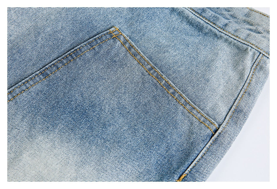 Close-up of a light-wash denim jeans pocket and golden contrast stitching.
