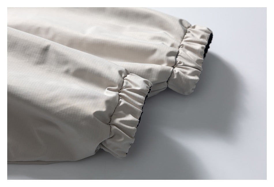 Close-up of pale beige fabric with gathered ruffled cuffs and narrow dark edging.