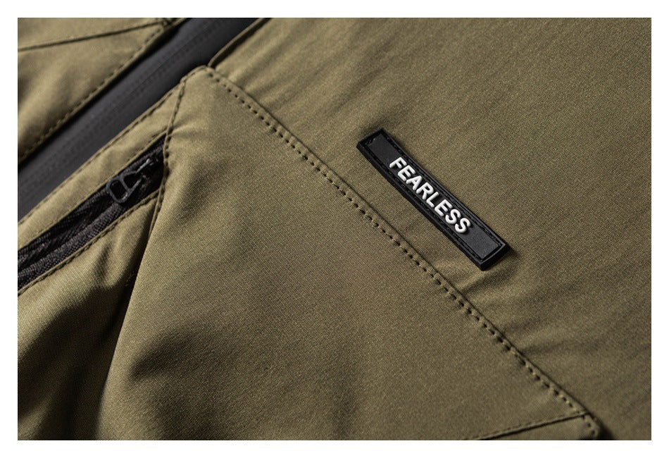 Close-up of an olive-khaki jacket pocket with a black zipper and a raised FEARLESS badge.