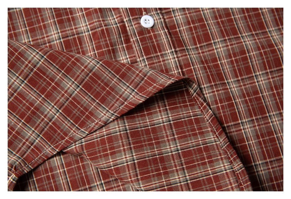 Close-up of the plaid shirt's chest pocket, stitching, and white button.