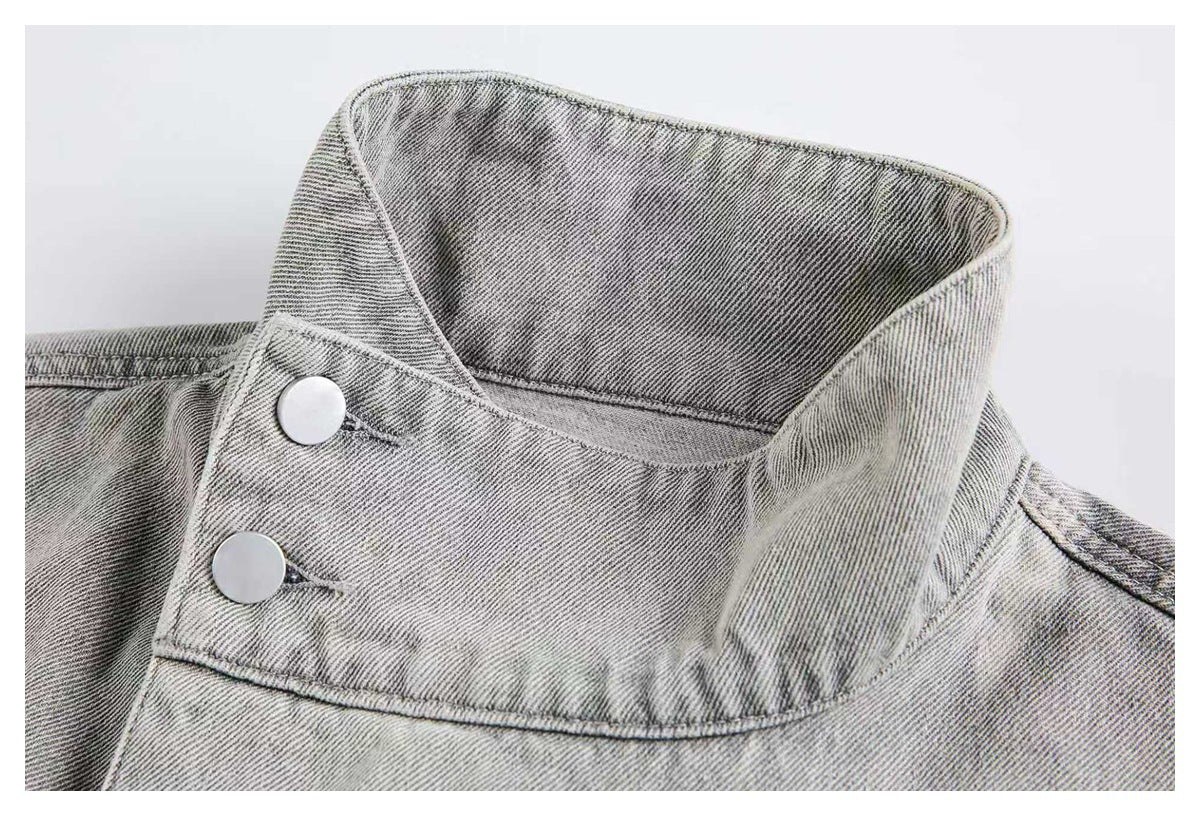 Close-up of a light gray jacket’s tall collar with two silver snap buttons.