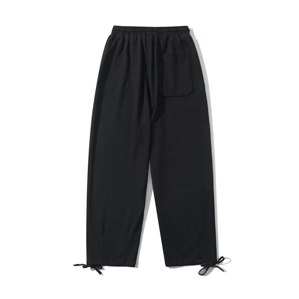 Black sweatpants, back flat lay, with elastic waistband, one rear patch pocket and ankle tie cords