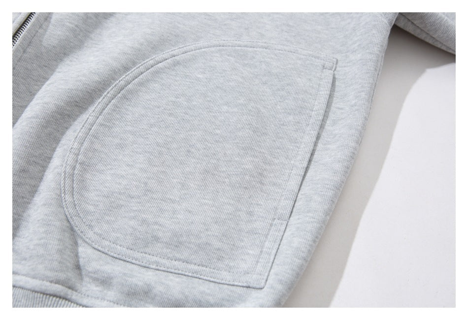 Close-up of a large curved patch pocket on a light gray zip-up jacket.