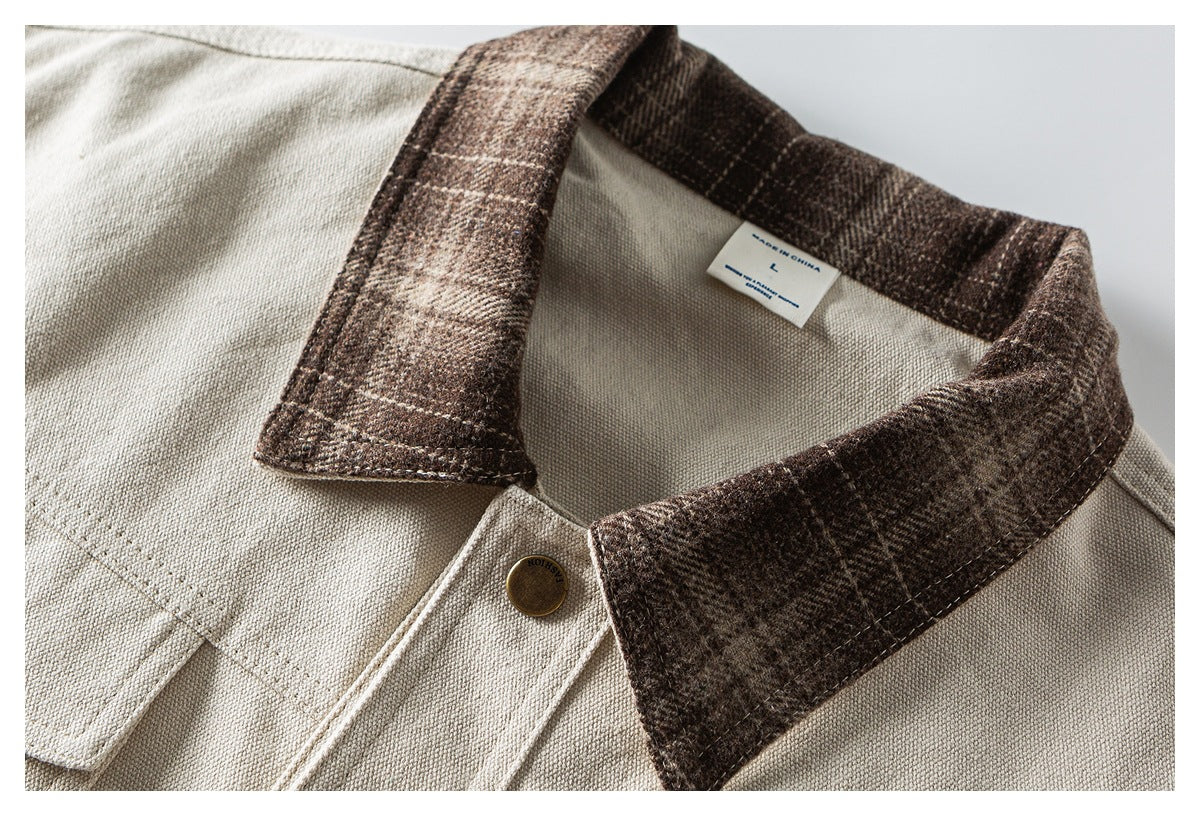 Close-up of a light beige shirt collar with dark brown plaid trim, a brass button and inner size label.