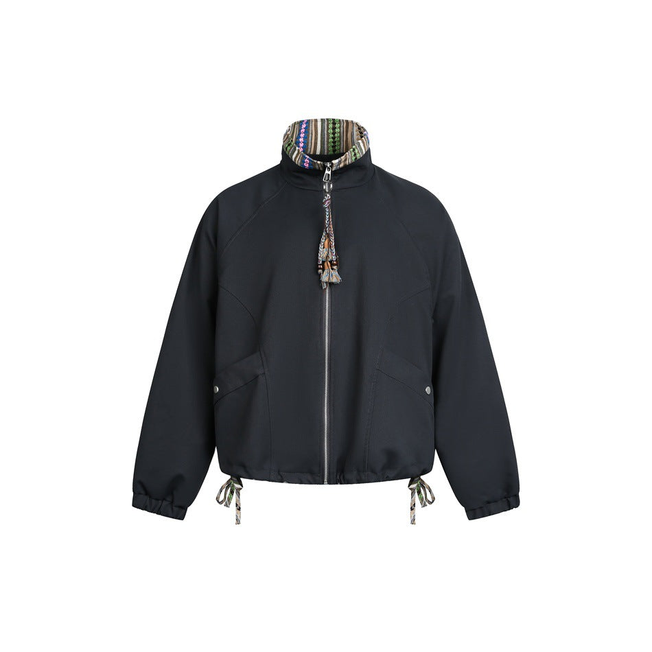 Front view of a dark jacket with a patterned stand collar, center zipper, angled pockets, and drawcords at the hem.