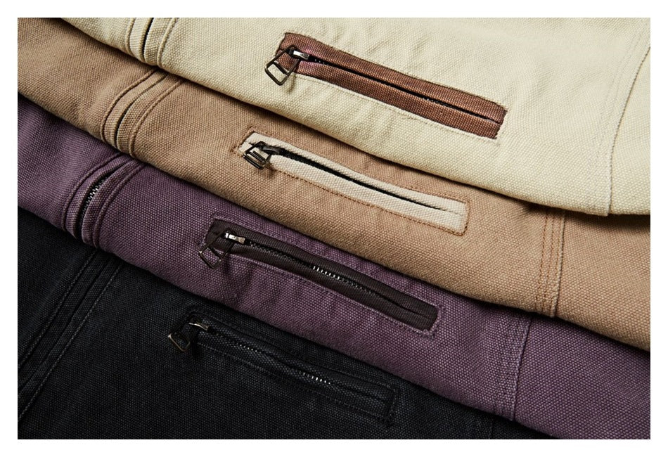 Four folded garments in cream, tan, purple, and black, each showing a zip pocket.