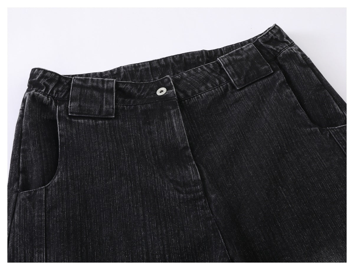 Close-up of black denim trousers showing the front waistband, button, belt loops, and pocket.