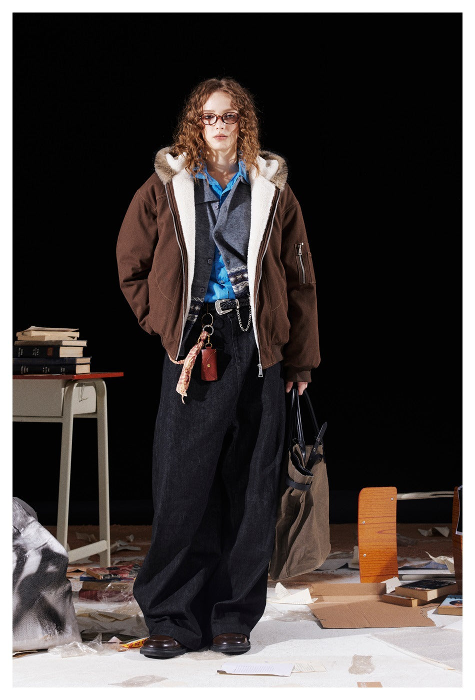 Full-length front view of a model wearing an open brown jacket with cream lining and a fur-trimmed hood.