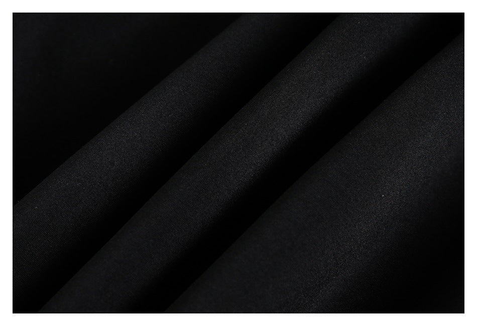 Close-up of black fabric arranged in soft folds, showing a fine, subtle woven texture.