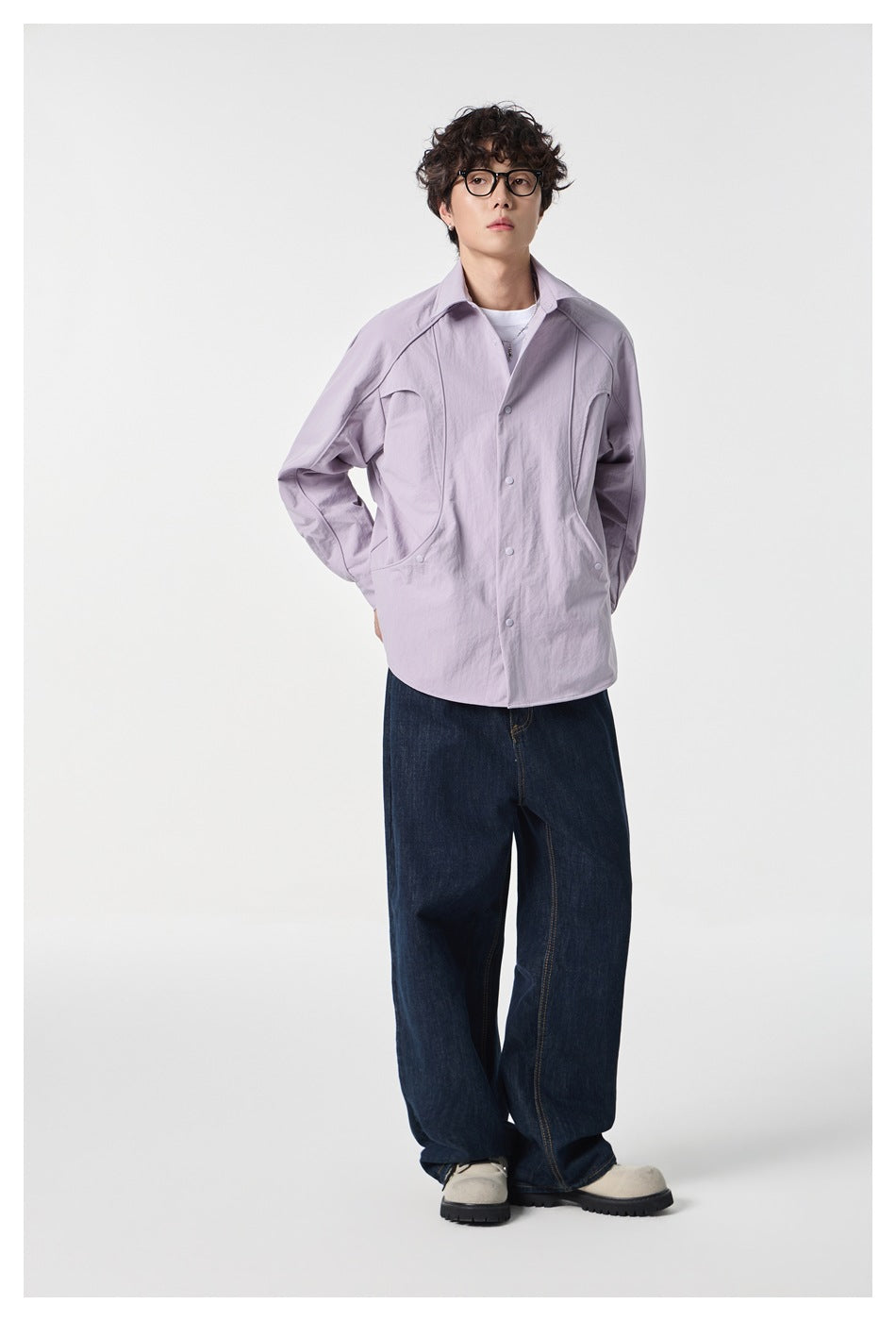 Full-length model wearing a pale lavender snap-front shirt, dark wide-leg jeans, and light shoes.