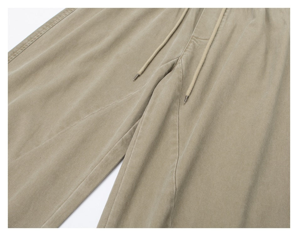 Close-up of beige pants showing drawstring tips, front seam construction, and fabric texture.