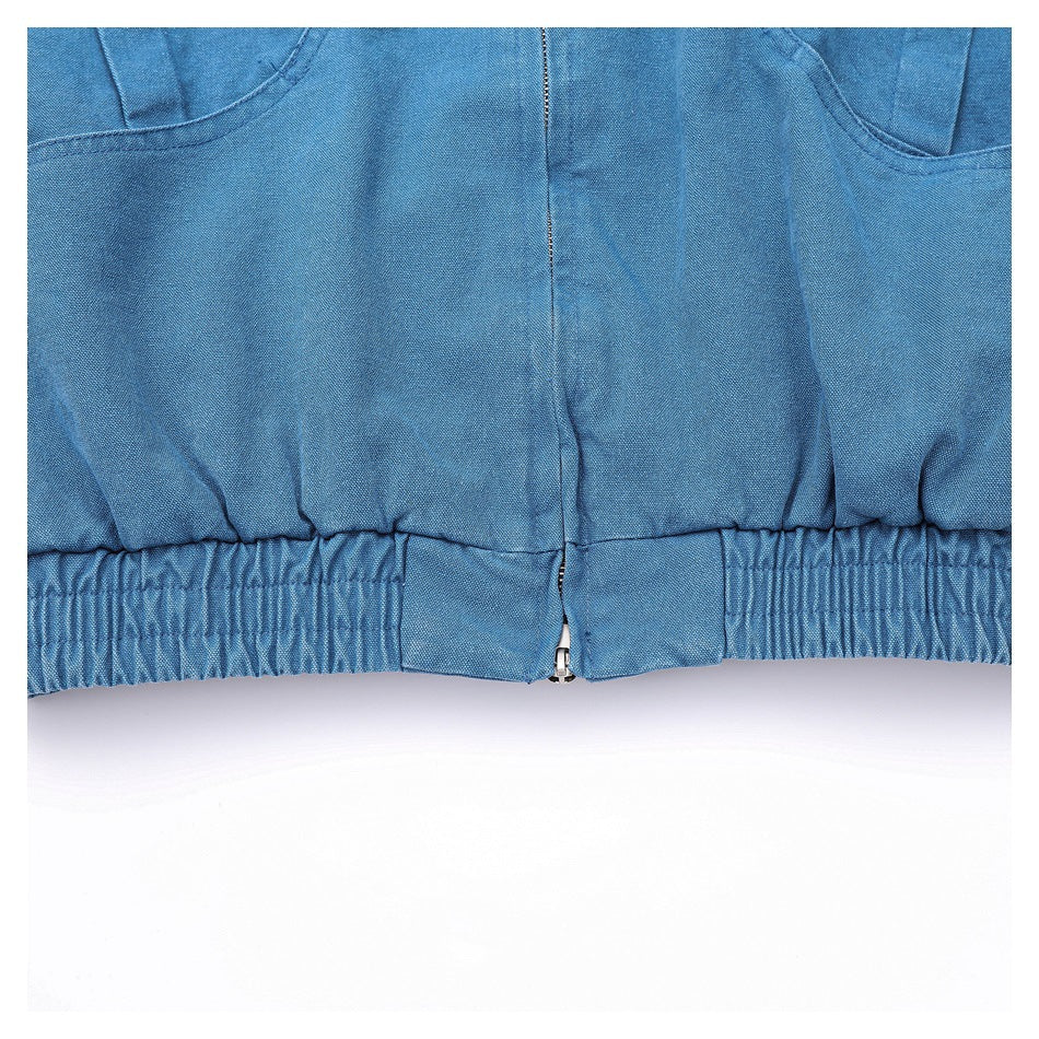 Close-up of the blue jacket's front pockets, center zipper, and gathered elastic hem.