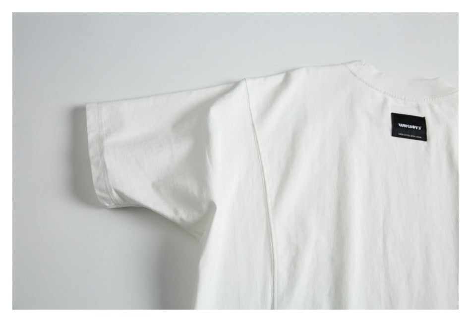 Partial flat lay of a white T-shirt with a small black sewn label near the neckline.