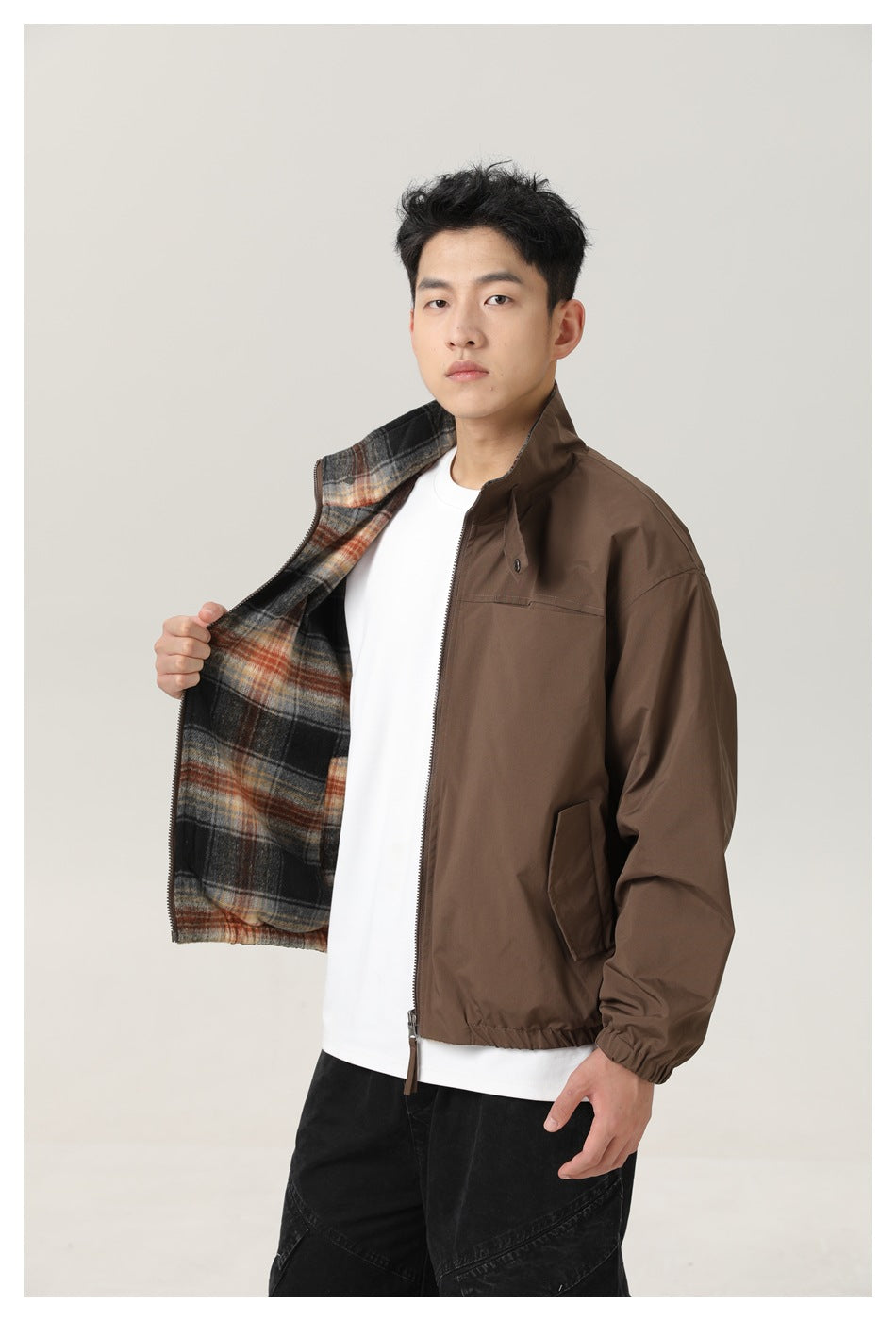 Model wears a brown zip jacket open to reveal its black, gray, and rust plaid lining.