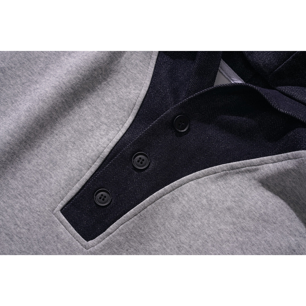 Close-up of the dark three-button placket and gray fabric on a hooded pullover.