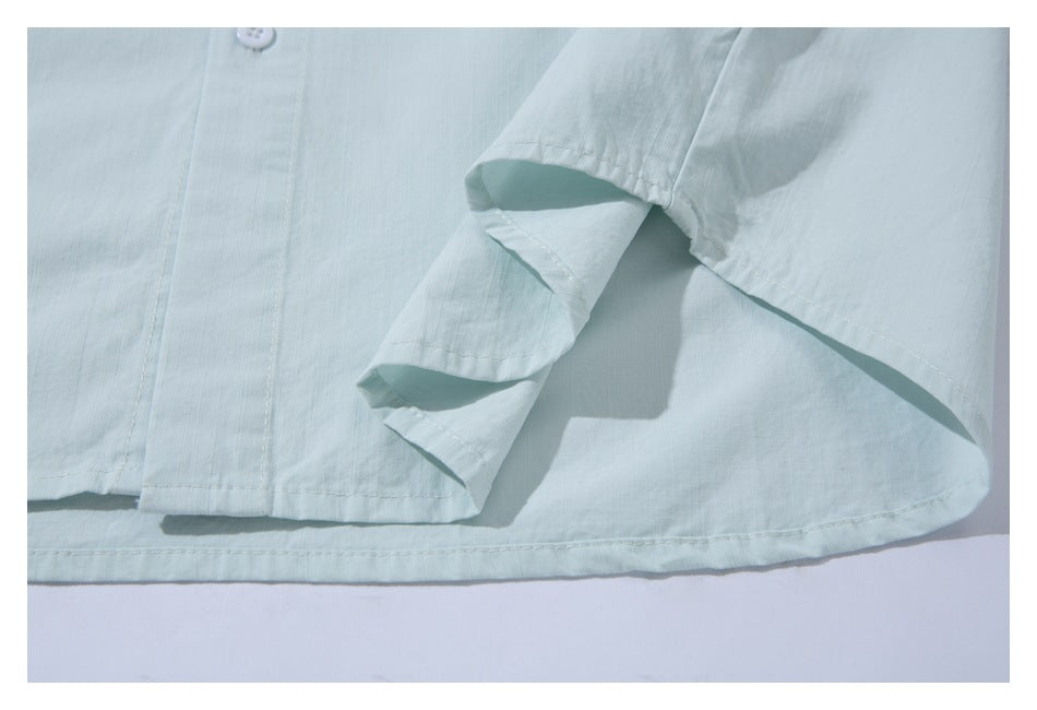 Close-up of a pale mint shirt's curved hem and side slit.
