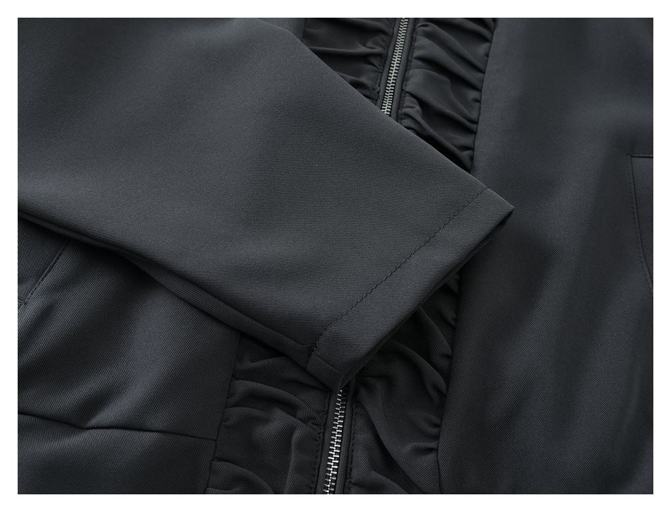 Close-up of a black sleeve with a stitched cuff beside the garment's front zipper.