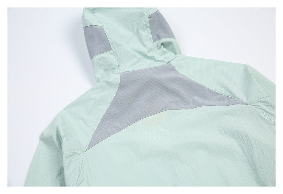 Upper back of a pale mint hooded jacket, with a broad gray panel across the shoulders.